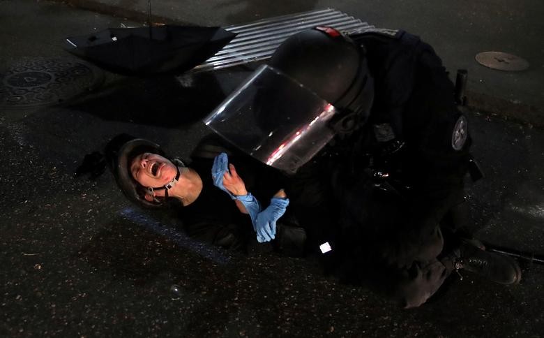 Demonstrator Dana Parks reacts as she is detained by a police officer during a protest against racial inequality and police violence in Portland, Oregon. REUTERS/Caitlin Ochs